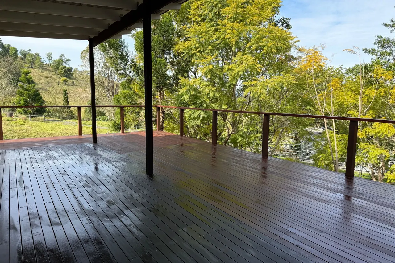 A covered timber deck looking out over hinterland hills and trees