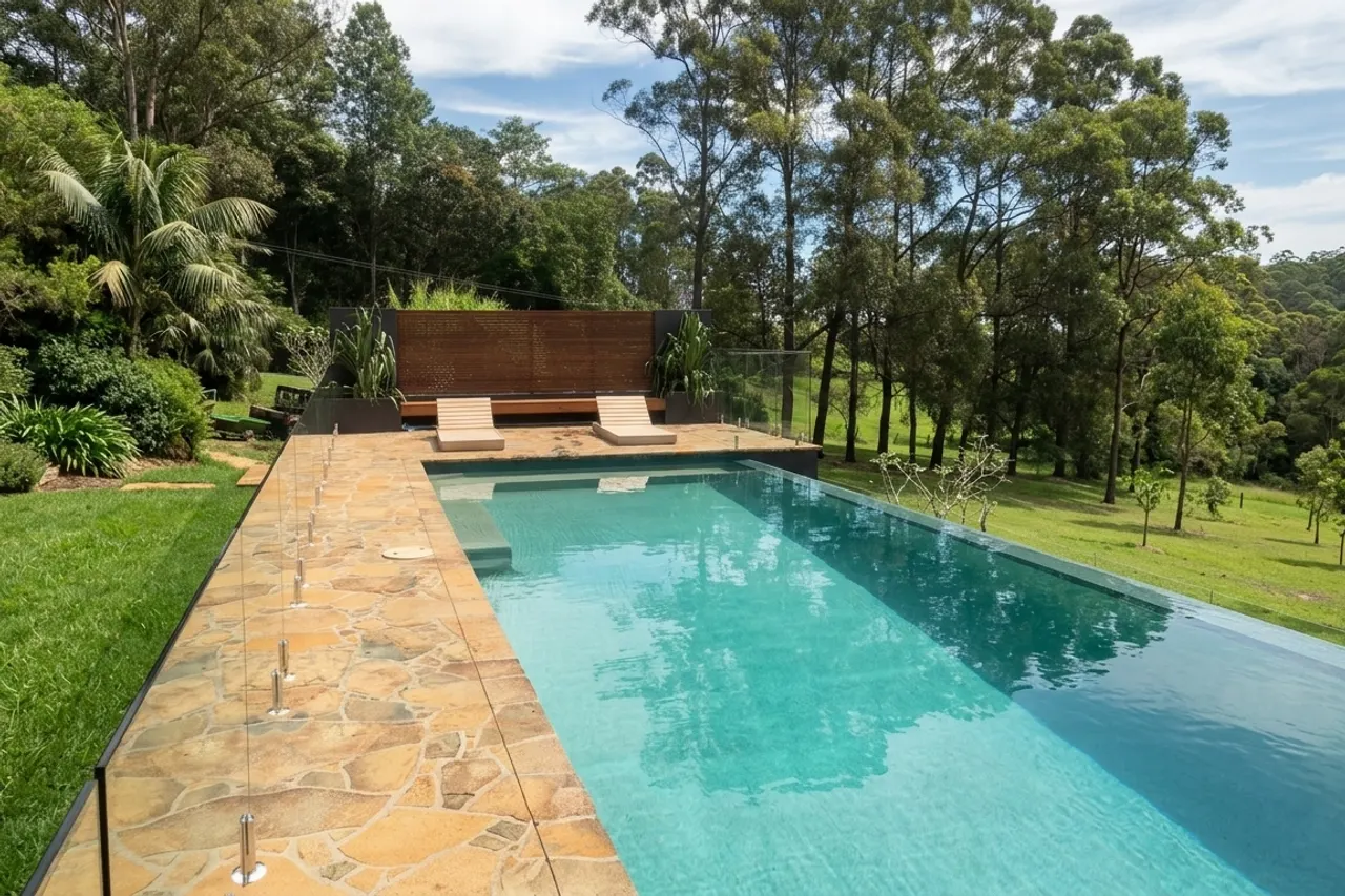 A pool with stone paving and a timber feature wall, bushland beyond