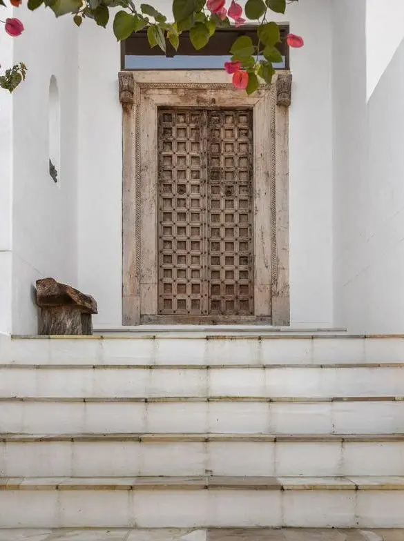 Carved front door at the top of white rendered steps