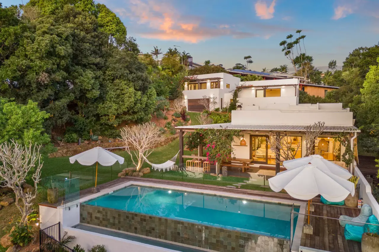 The house above the infinity pool and lawn at dusk