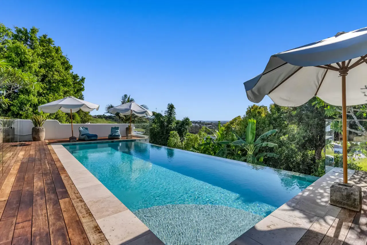 Infinity-edge pool with a timber deck and garden views